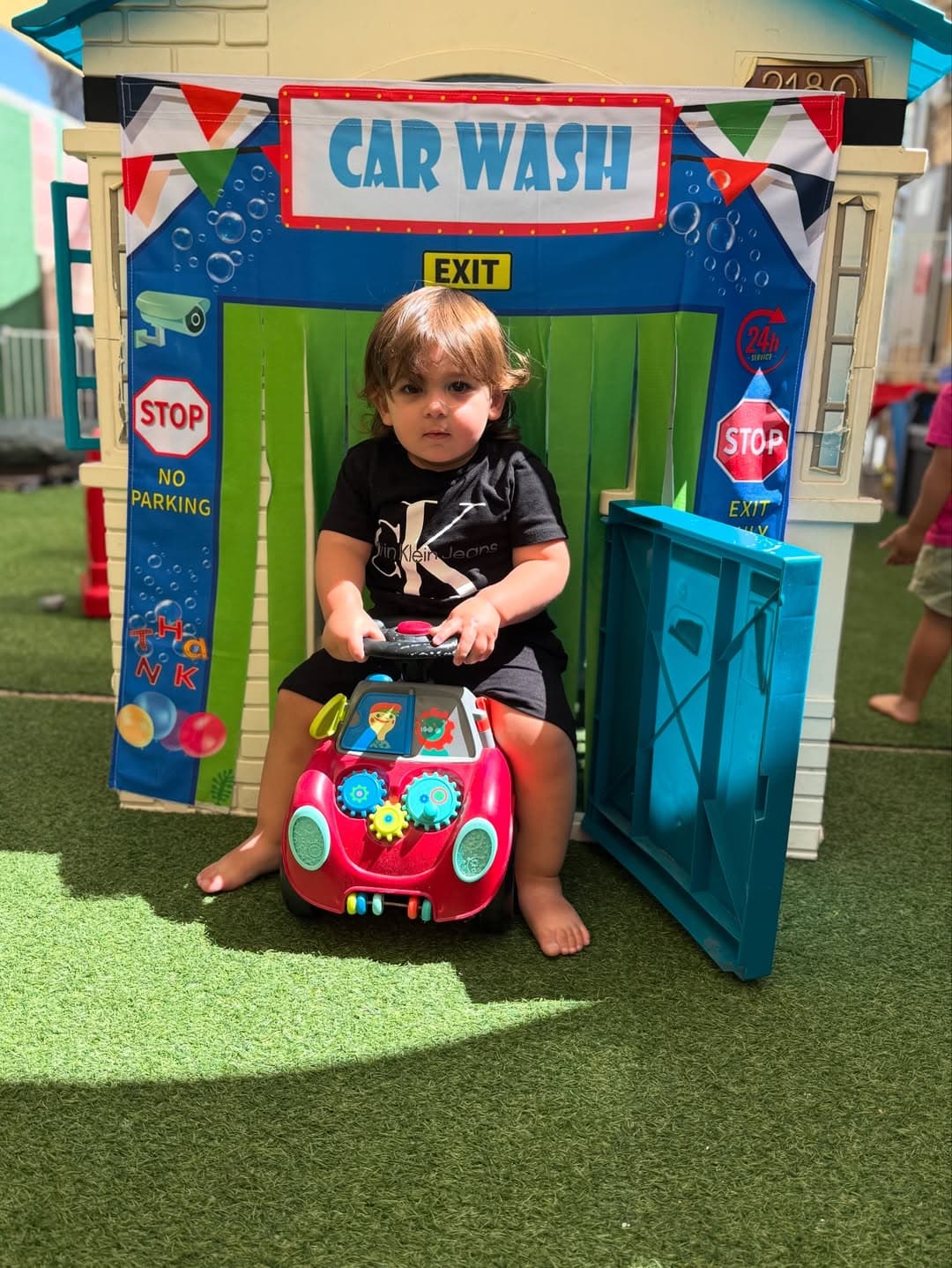 Two children scrubbing a toy car with soap and cloths during Car Wash day