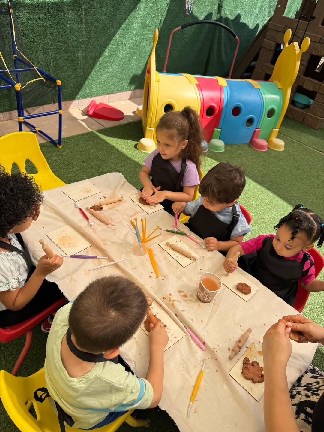 Children shaping clay together outdoors