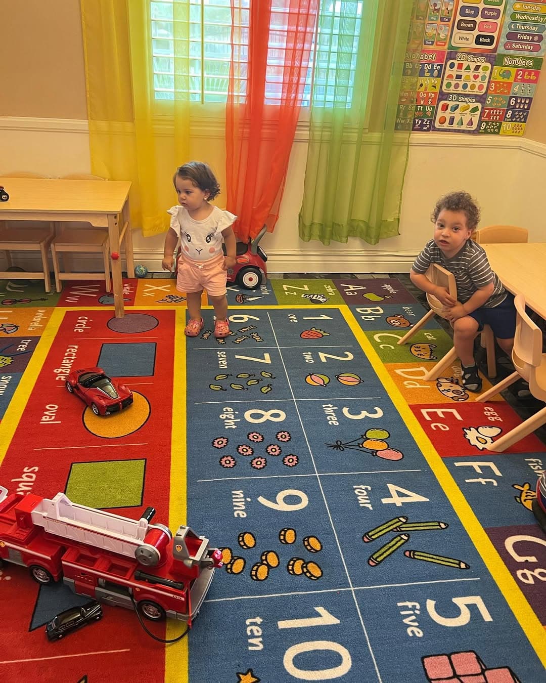 Children playing with toy vehicles on the alphabet and numbers rug