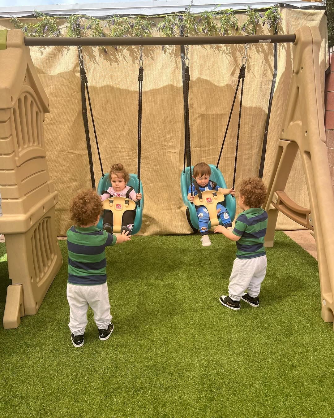 Older children pushing toddlers on outdoor swings